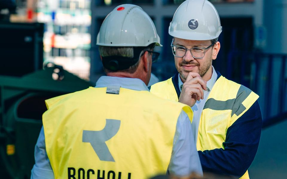 Zwei Bauleiter in Warnwesten und Helmen im Gespräch auf der Baustelle der Uniq Towers in Düsseldorf